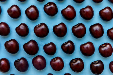 picture of a bright burgundy cherry on a blue background.