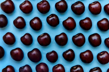 picture of a bright burgundy cherry on a blue background.