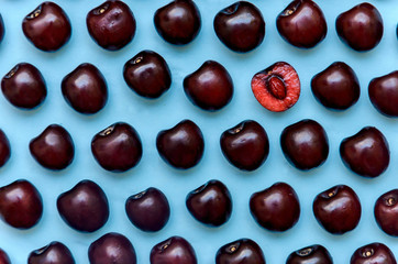 picture of a bright burgundy cherry on a blue background.