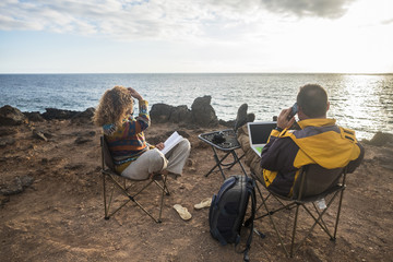 nice couple enjoying a sunset at the end of the day. travel lifestyle in wanderlust for happy cacucasian people. working alternative office with laptop and mobile connection to internet. photographers