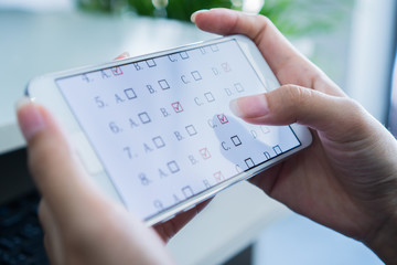 Student testing E-learning exam on tablet computer with multiple choice questions by finger...