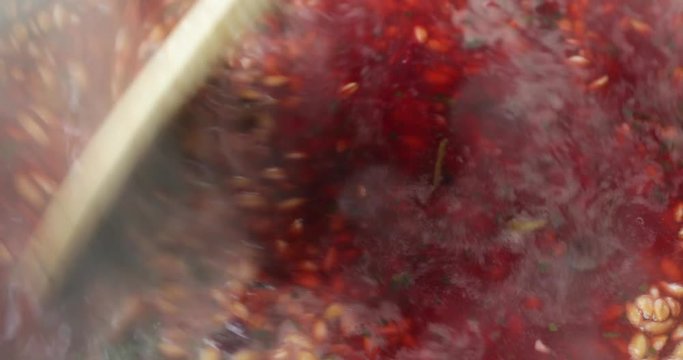 Very close video of stirring farro with beets and spinach and seasonings in boiling water with a wood spoon.