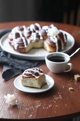 Traditional Cinnamon Rolls with Icing Glaze, on round wooden table.
