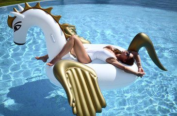  woman relaxing in luxury swimming pool resort hotel on big inflatable unicorn floating pegasus...