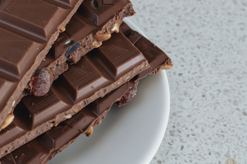 Milk chocolate with nuts and raisins on a white plate