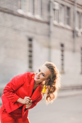 Fototapeta premium Portrait of a beautiful bright girl street style lifestyle smiling and posing in a red suit on a sunny day