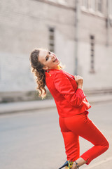 Portrait of a beautiful bright girl street style lifestyle smiling and posing in a red suit on a sunny day