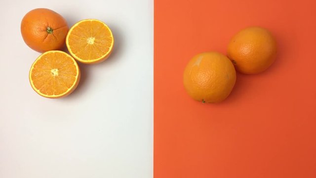 Dos naranjas rodando se paran frente a otra cortada por la mitad.