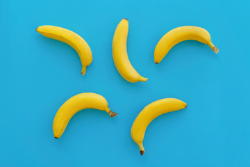 yellow bananas on bright blue paper, trendy background. fruits modern flat lay. juicy summer vitamin abstract background, top view. pop art style. banana pattern. blog