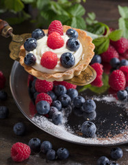  Dessert tarts with raspberries and blueberries on a wooden table.
