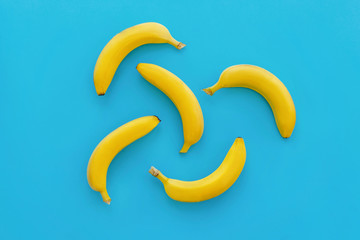 yellow bananas on bright blue paper, trendy background. fruits modern flat lay. juicy summer vitamin abstract background, top view. pop art style. banana pattern. blog