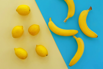 yellow bananas and lemons on bright blue paper, trendy flat lay. fruits modern image, top view. juicy summer vitamin abstract background. pop art style. creative minimalism.