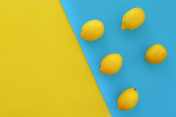 yellow  lemons on bright blue paper, trendy flat lay. fruits modern image, top view. juicy summer vitamin and diet concept. pop art style. creative minimalism. space for text