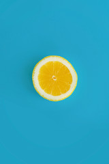 yellow slice of lemon on bright blue paper, trendy flat lay. fruits modern image, top view. juicy summer vitamin and diet concept. pop art style. creative minimalism pattern