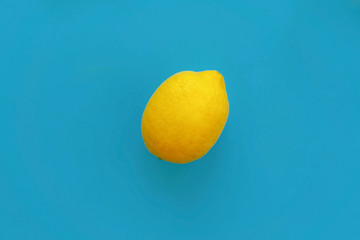 bright yellow lemon on blue paper flat lay. trendy stylish background, fruit top view. space for text