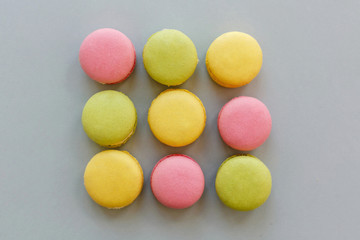 colorful macarons on trendy pastel gray paper, flat lay. tasty pink, yellow, green and brown macaroons. candy bar for party. food photography. yummy background. macaron pattern.
