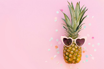 summer vacation concept. pineapple in pink sunglasses on trendy pink paper background with confetti. minimalism flat lay.  party concept. space for text. summer holidays.
