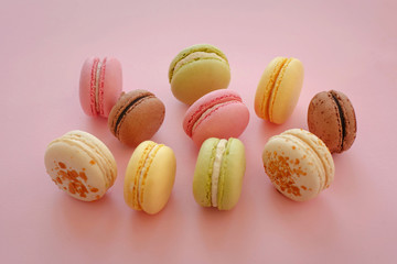 food photography of tasty colorful macarons  on trendy pastel pink paper. space for text pink, yellow, green, white, brown macaroons. yummy background. diet concept. luxury catering
