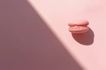 Fotobehang tasty pink macaron in sunny light on trendy pastel pink paper flat lay. space for text. pink macaroon in light contrast. modern food photography concept. minimalism concept © sonyachny