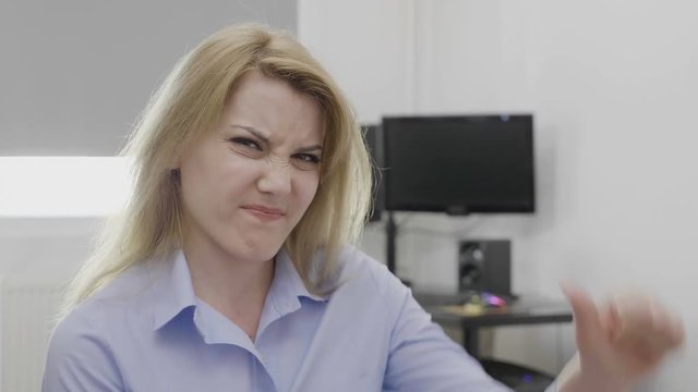 Disgusted young businesswoman showing thumbs down sign of dislike