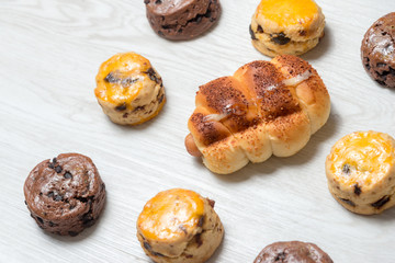 closeup delicious sausage bread roll and fresh tasty scones on wooden table