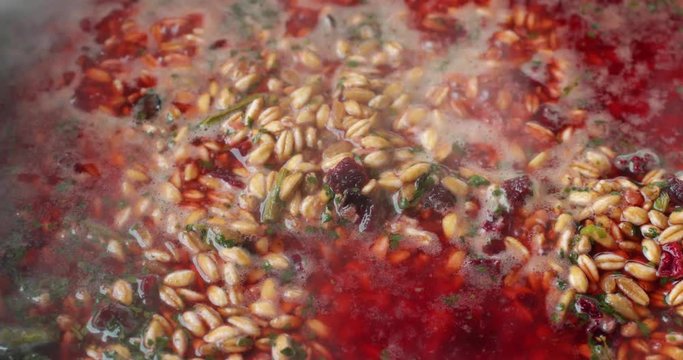 Close video of farro with beets and spinach and seasonings cooking in boiling water.