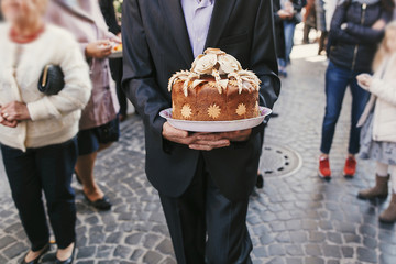man walking and holding traditional ukrainian wedding cake with roses. delicious brown bread