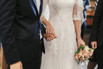 beautiful bride and groom hands exchanging wedding rings in church during wedding ceremony. spiritual holy matrimony. wedding couple and priest putting on rings