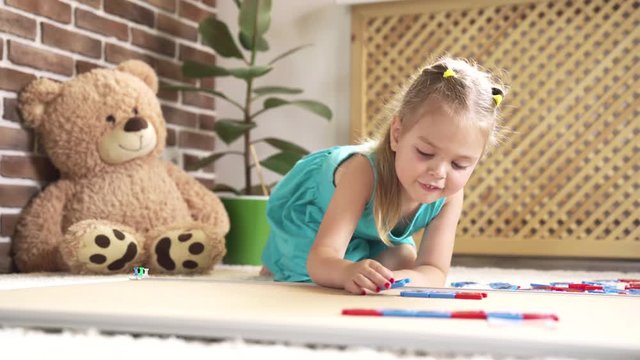 Small cute girl playing with puzzle and collects words from the letters. 4K video.