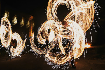 amazing fire show at night at festival or wedding party. Fire dancers swing, spinning fire and man juggling with bright sparks in the night. fire show performance and entertainment