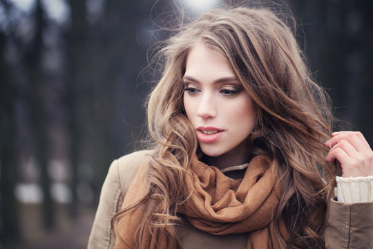 Beautiful young woman walking in park. Female model face closeup,  outdoor portrait