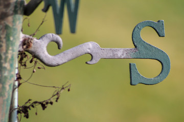 A close-up of the South wind direction indicator of an old weather vane