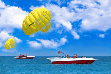 Parasailing water amusement. Flying on a parachute behind a boat on a summer holiday by the sea in...