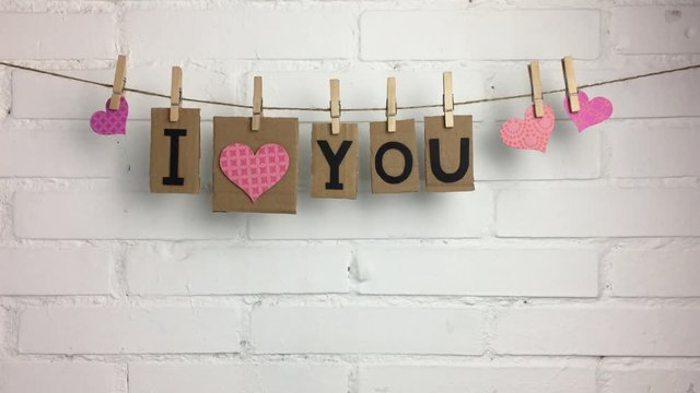 Frase &ldquo;I love you&rdquo; y corazones colgando de una cuerda con pinzas