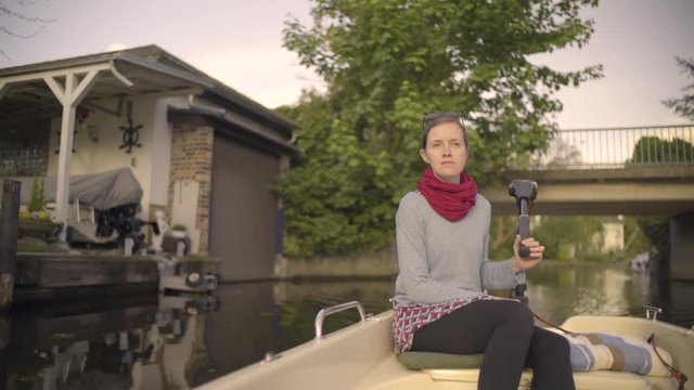 Frau im Boot fährt mit Elektro Motor auf dem Wasser und lenkt es