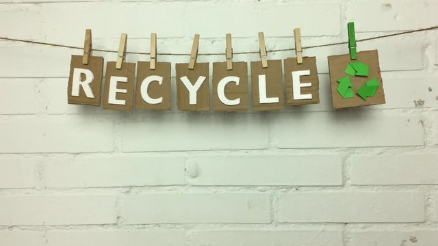 Palabra recycle en ingles, sujeta en una cuerda con pinzas.