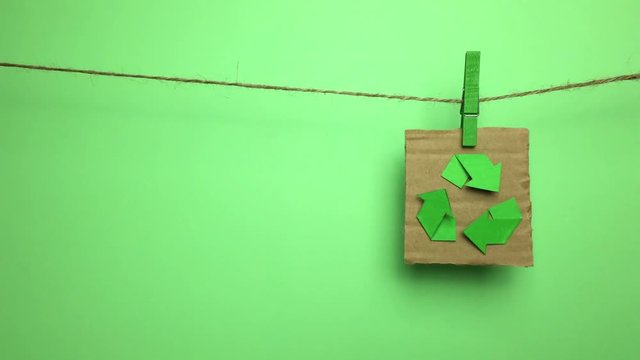 Simbolo de reciclar colgado de una cuerda con pinza.