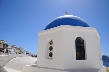 Fototapeta na wymiar Famous stunning view of white architectures and church above the volcanic caldera in the village of Oia in Santorini island, Greece