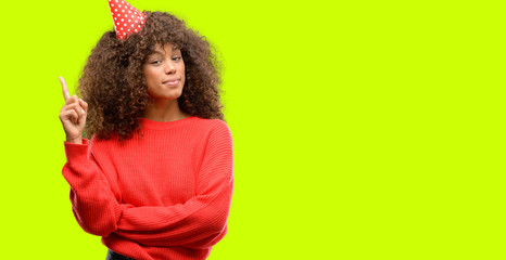 African american woman celebrates birthday surprised with an idea or question pointing finger with happy face, number one