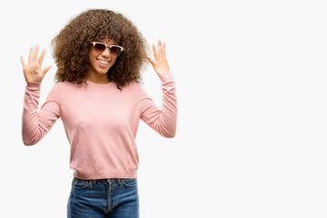 African american woman wearing pink sunglasses showing and pointing up with fingers number nine...
