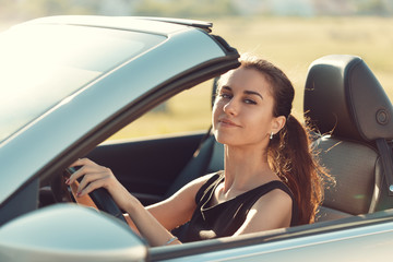 Fototapeta na wymiar young girl driving cabrio car, on sunset light