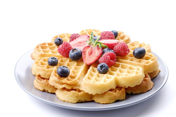 Festive breakfast composition with homemade waffles and variety of different summer berries and mint leaves.