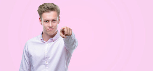 Young handsome blond man pointing with finger to the camera and to you, hand sign, positive and confident gesture from the front