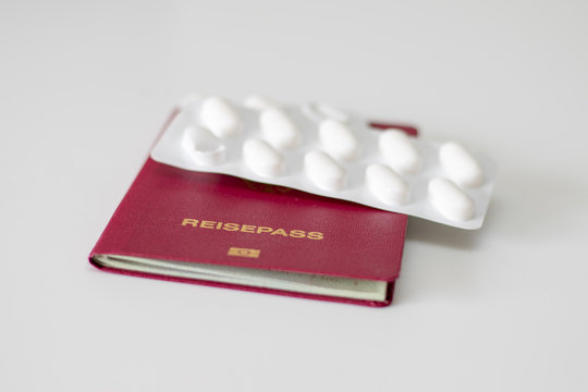 Deutscher Reisepass mit daraufliegender wei&szlig;en Tablettenpackung als Reiseapotheke auf wei&szlig;em Hintergrund