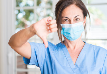 Middle aged doctor woman with angry face, negative sign showing dislike with thumbs down, rejection concept