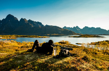 Lofoten - Panorama in Nordnorwegen, ein Mann/Wanderer liegt auf dem Berg und blickt in den Fjord 