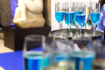 The waiters greet guests with alcoholic drinks. Champagne, blue wine, white wine on trays.