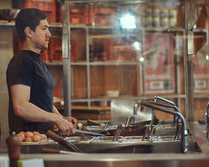 Cooking process in an Asian restaurant. Cook is stirring vegetables in wok.