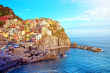 Fototapeta na wymiar Charming beautiful landscape with bright colored houses on the rock on the seafront of Manarola in Cinque Terre, Liguria, Italy, Europe in sunlight