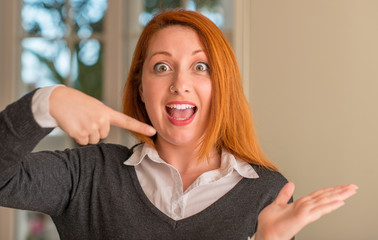 Redhead woman at home very happy pointing with hand and finger